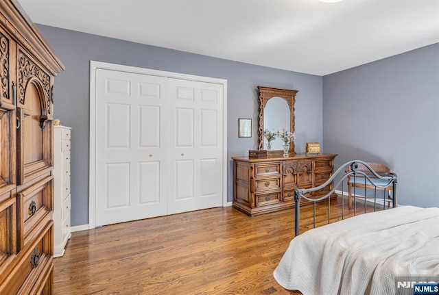 bedroom featuring baseboards, wood finished floors, and a closet