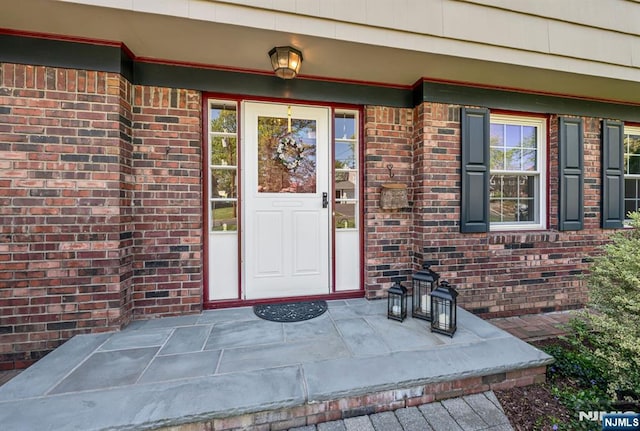doorway to property with covered porch and brick siding