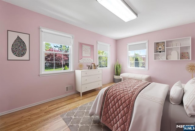 bedroom with baseboards, visible vents, and wood finished floors
