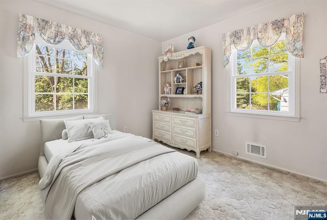 bedroom featuring visible vents, baseboards, multiple windows, and light colored carpet