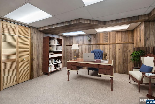 office space with wood walls, carpet, and a paneled ceiling