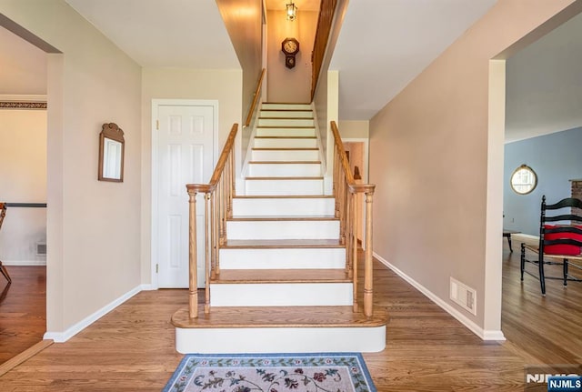 stairway with visible vents, baseboards, and wood finished floors