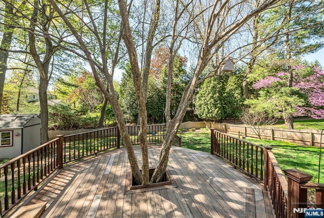 wooden deck featuring a lawn, a fenced backyard, and an outdoor structure