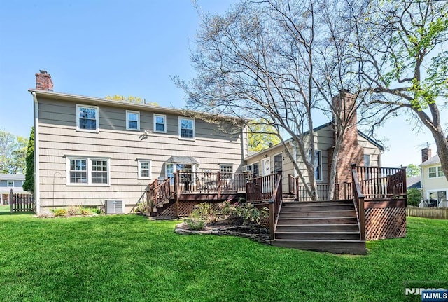 back of property with a chimney, a lawn, a deck, fence, and stairs