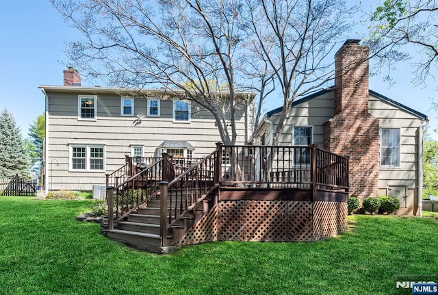 rear view of house with a lawn, a deck, a chimney, and stairs