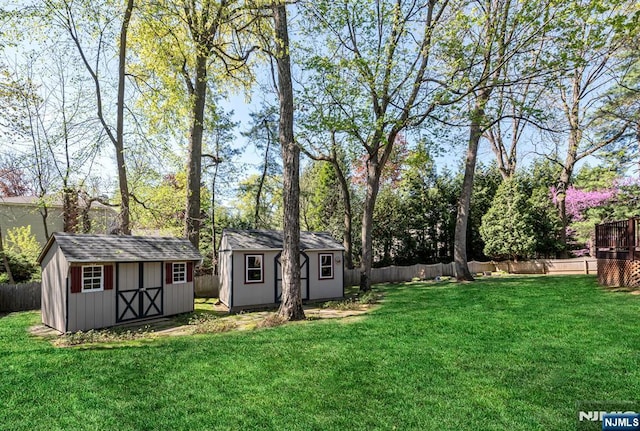 view of yard featuring an outdoor structure, a fenced backyard, and a storage unit