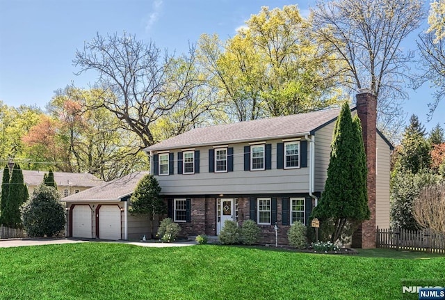colonial inspired home featuring a chimney, a front yard, fence, concrete driveway, and an attached garage