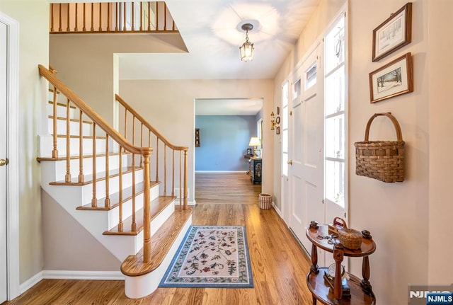 foyer entrance with wood finished floors, a wealth of natural light, and stairway
