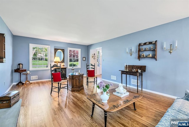 living area with baseboards, wood finished floors, and visible vents