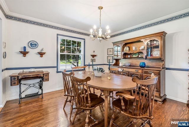 dining room featuring crown molding, dark wood finished floors, baseboards, and a notable chandelier