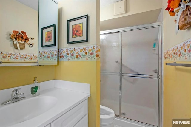 bathroom featuring vanity, a shower stall, and toilet