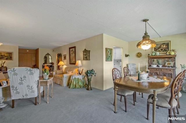 carpeted dining space with a textured ceiling