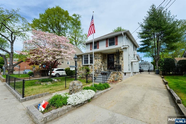 view of front of house with a fenced front yard, driveway, and stone siding