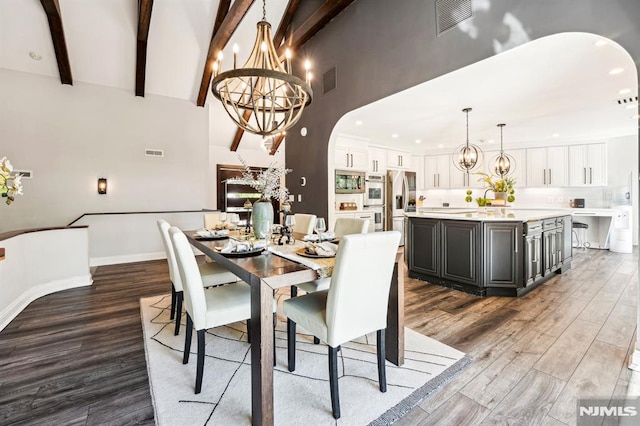 18 Fairview Dr, North Caldwell, NJ 07006 - dining space featuring arched walkways, a chandelier, wood finished floors, high vaulted ceiling, and beam ceiling