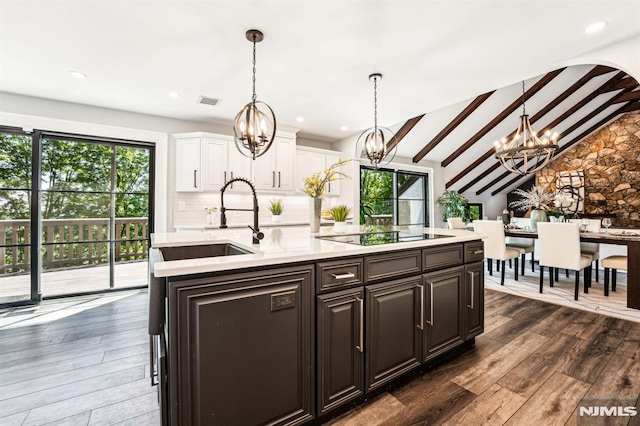 18 Fairview Dr, North Caldwell, NJ 07006 - kitchen with a chandelier, black electric stovetop, light countertops, white cabinetry, and healthy amount of natural light