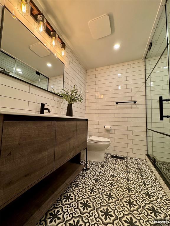 18 Fairview Dr, North Caldwell, NJ 07006 - bathroom with vanity, toilet, a shower stall, tile walls, and tile patterned floors
