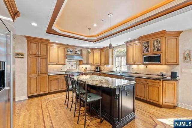 kitchen with appliances with stainless steel finishes, brown cabinetry, light wood-style flooring, and a center island