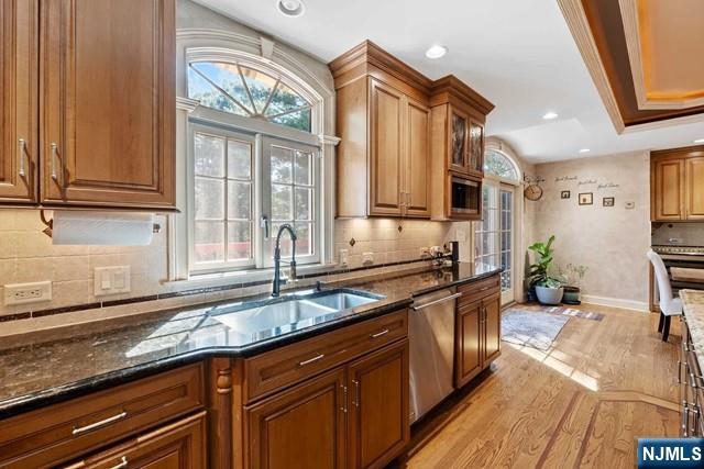 kitchen featuring a sink, plenty of natural light, light wood-style floors, and dishwasher