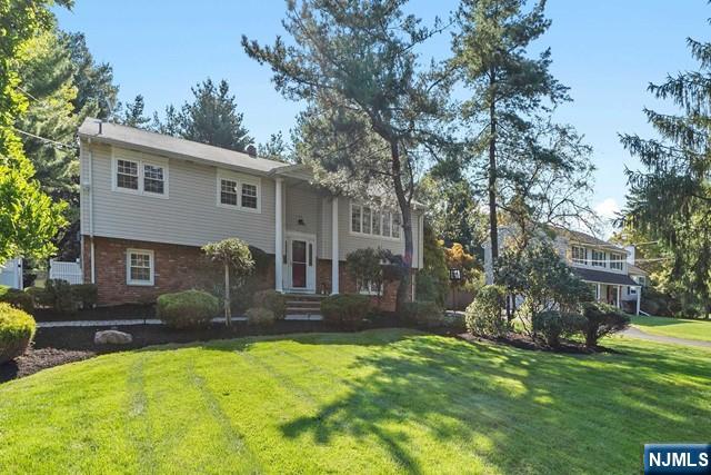 raised ranch with brick siding and a front yard