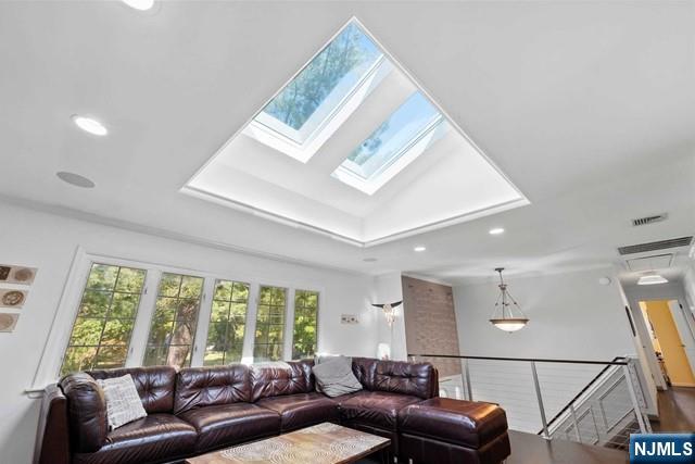 living area featuring recessed lighting, a skylight, visible vents, and a raised ceiling