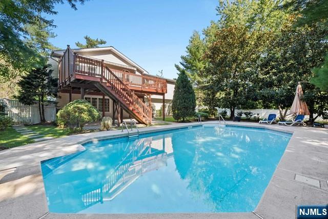 view of swimming pool with fence, a wooden deck, stairway, a fenced in pool, and a patio area