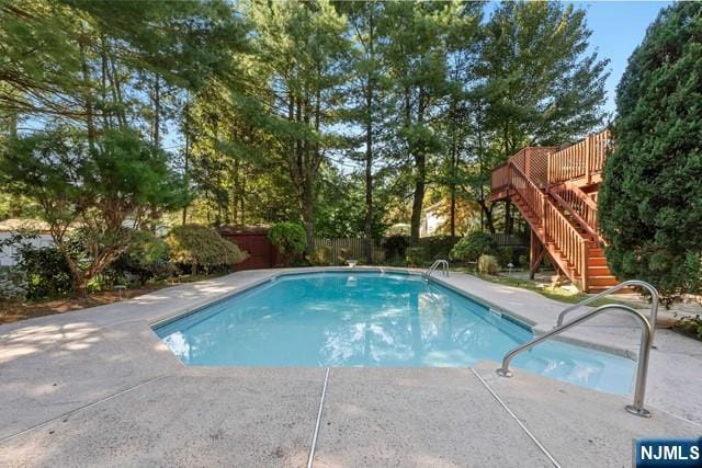 view of swimming pool with a wooden deck, a patio, a fenced backyard, a fenced in pool, and stairs