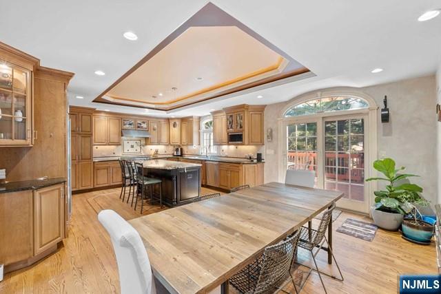 dining area featuring recessed lighting, a wealth of natural light, a raised ceiling, and light wood-style floors