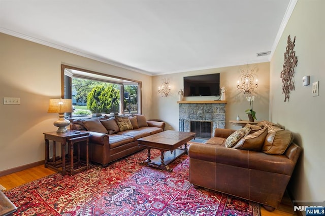 living area with a stone fireplace, visible vents, crown molding, wood finished floors, and baseboards