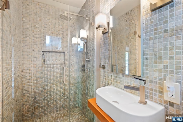 bathroom featuring tile walls, a shower stall, and a sink
