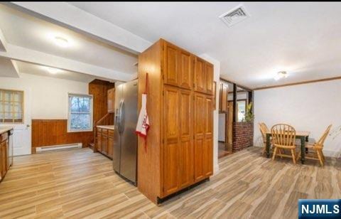 kitchen featuring visible vents, brown cabinetry, light wood-style floors, and a baseboard heating unit