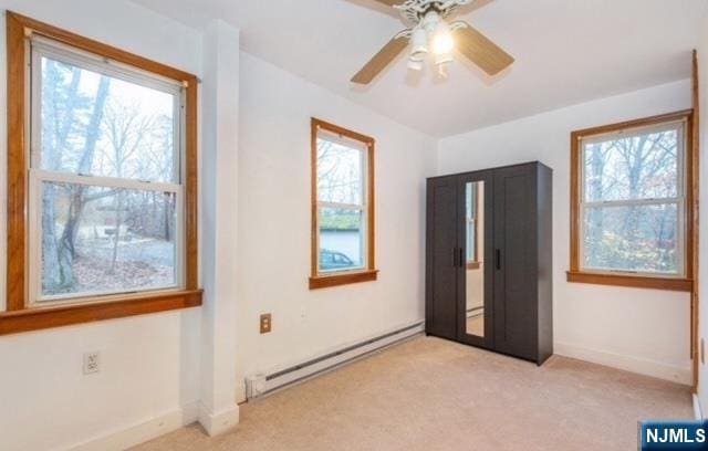 unfurnished bedroom with light colored carpet, multiple windows, and baseboard heating