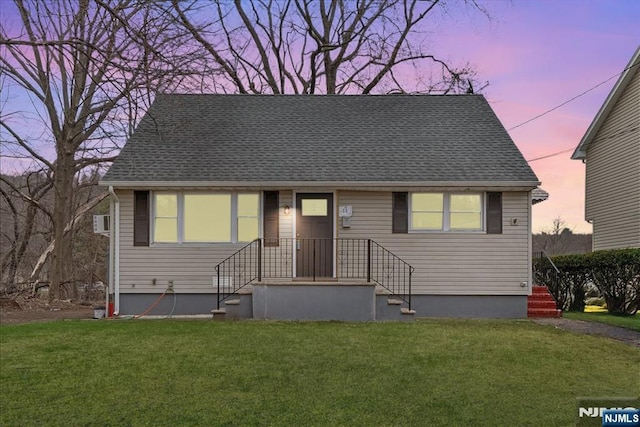 view of front of house with a shingled roof and a front yard
