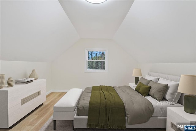bedroom featuring baseboards, lofted ceiling, and light wood-type flooring