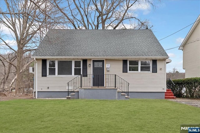 view of front facade with a shingled roof and a front lawn