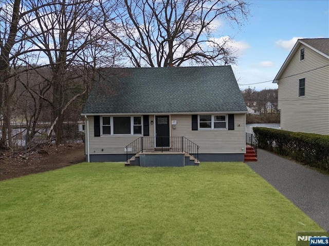 view of front of house with a front lawn and roof with shingles