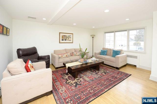 1-06 Lambert Rd, Fair Lawn, NJ 07410 - living area with radiator heating unit, recessed lighting, baseboards, wood finished floors, and visible vents