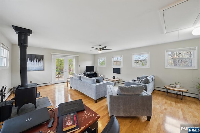 living area featuring attic access, light wood finished floors, a ceiling fan, and a baseboard radiator