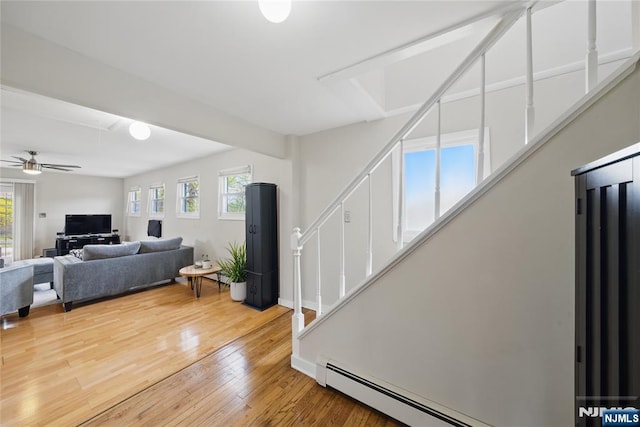 living room featuring stairway, plenty of natural light, wood finished floors, and ceiling fan