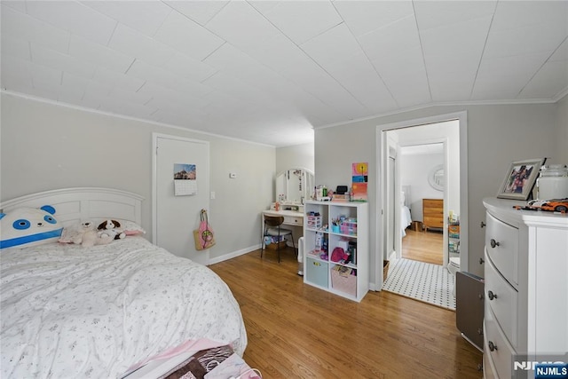 bedroom with crown molding, baseboards, and wood finished floors