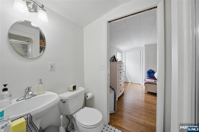 bathroom with a sink, toilet, wood finished floors, and lofted ceiling