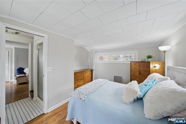 bedroom featuring crown molding, baseboards, light wood-style flooring, and visible vents