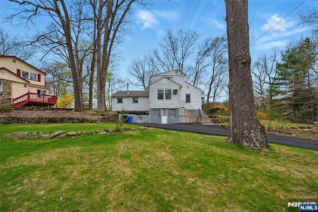 back of property with a lawn and stairway