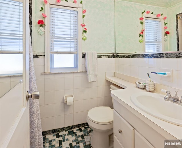 bathroom with toilet, tile walls, and vanity