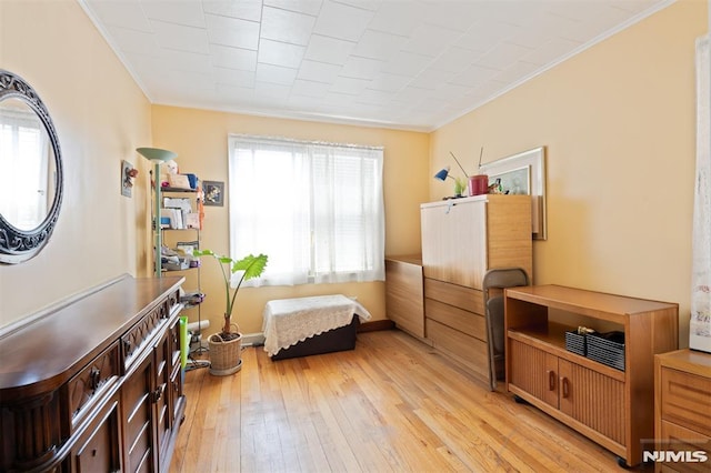living area with ornamental molding and light wood-style flooring