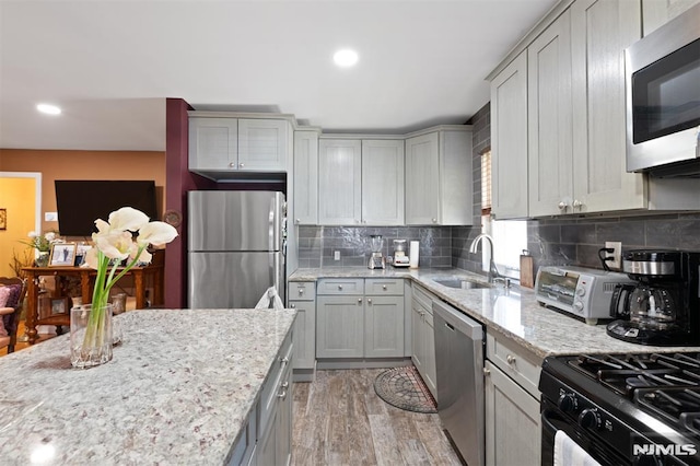 kitchen featuring gray cabinets, a sink, light wood finished floors, and stainless steel appliances