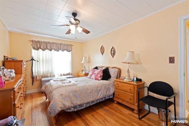 bedroom with light wood-style floors, baseboards, ornamental molding, and a ceiling fan