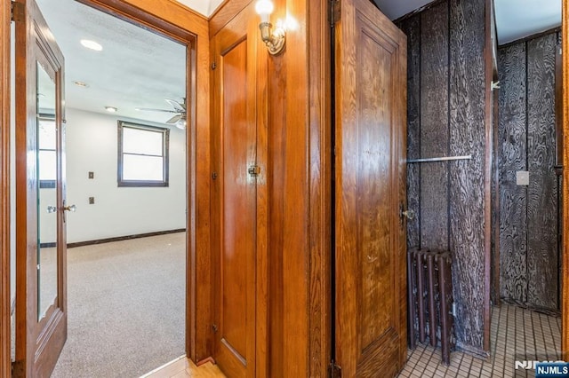 hall featuring baseboards and light carpet