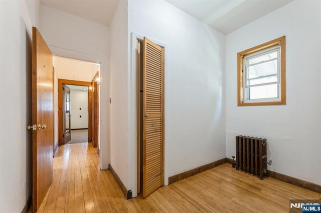 hallway with baseboards, light wood finished floors, and radiator heating unit