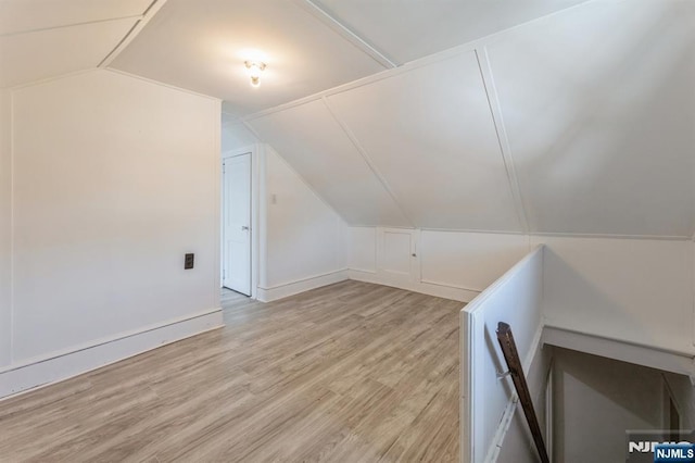additional living space with light wood-style flooring and vaulted ceiling