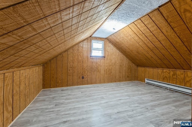 additional living space featuring wood walls, wood finished floors, vaulted ceiling, and a baseboard radiator